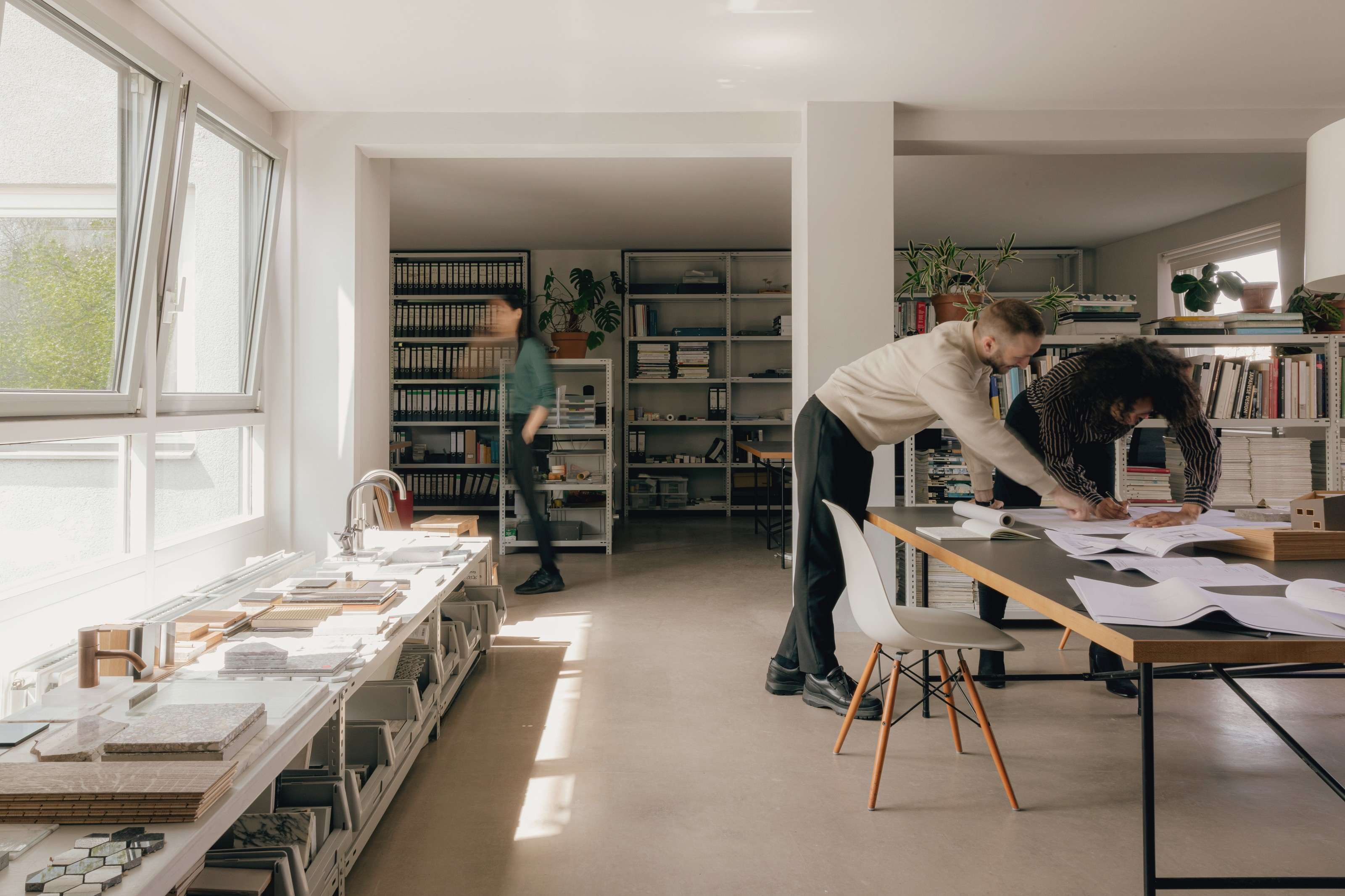 A bright studio: two people working on drawings at a large table